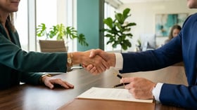Two B2B executives shaking hands over a contract document