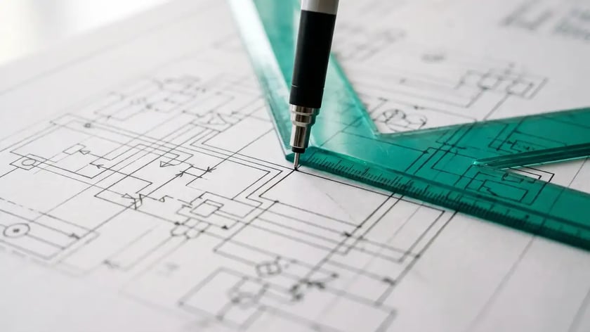 Architect's desk with precision blueprint and teal ruler representing the Intelligence-First approach to AI system design