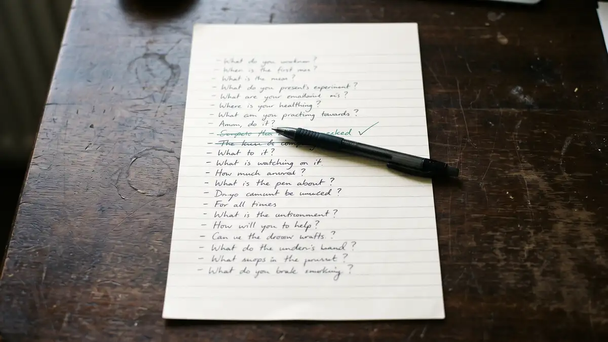 A handwritten list of buying questions on a sheet of paper with one line ticked in green